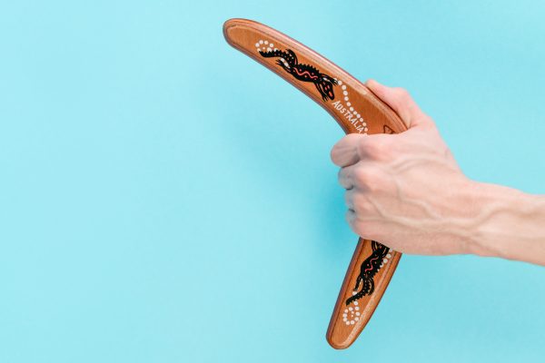 wooden boomerang in a man s hand closeup on a blue 2022 08 01 04 54 19 utc