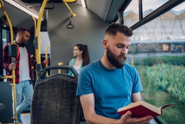 man is riding in a bus and reading a popular ficti 2022 09 06 15 45 48 utc